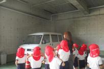 駐車場の高い所にある蛍光灯の上に作られたツバメの巣を真剣に見ている子ども達。